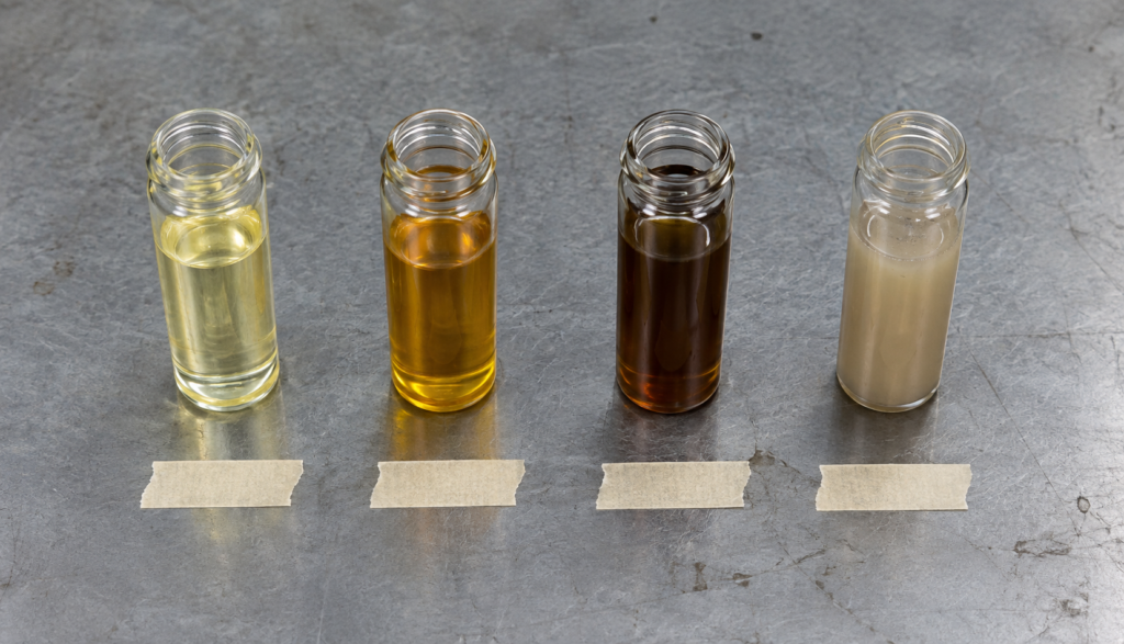 Side-by-side vials comparing new, aged, and contaminated brake fluid color